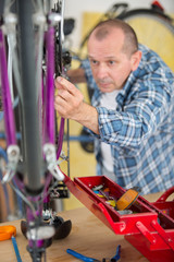 mechanic serviceman adjusting bicycle gear on wheel in workshop