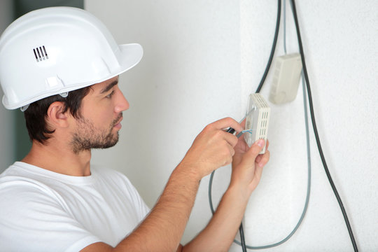electrician man worker installing a thermostat