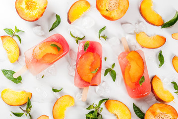 Summer desserts. Frozen drinks. Sweet fruit popsicles from frozen peach tea with mint. On a white marble table, with ingredients - peaches, mint, ice. Copy space top view
