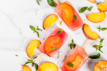 Summer desserts. Frozen drinks. Sweet fruit popsicles from frozen peach tea with mint. On a white marble table, with ingredients - peaches, mint, ice. Copy space top view