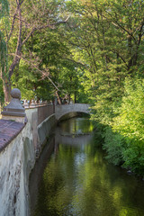 Bridge, water canal and lush trees on the Kampa Island in Prague, Czech Republic.