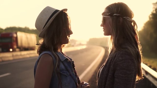Portrait of two girls in hippie clothes at dawn. Girlfriends are sensually looking at each other