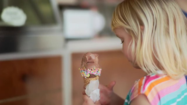 Little Girl Enjoys Chocolate Ice Cream Cone With Sprinkles In Local Ice Cream Shop