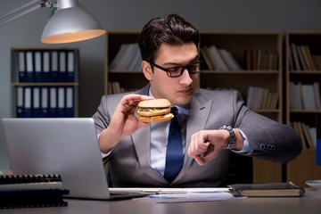 Businessman late at night eating a burger