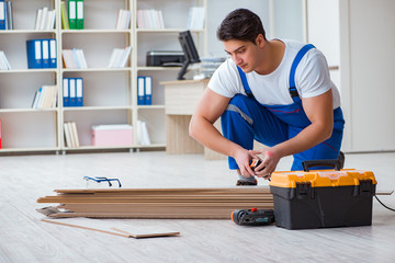 Young worker working on floor laminate tiles