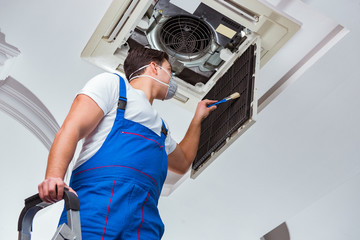 Worker repairing ceiling air conditioning unit
