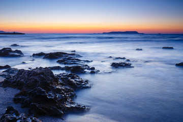 Fototapeta na wymiar sunset over the sea and wave washing up the beach, long exposure