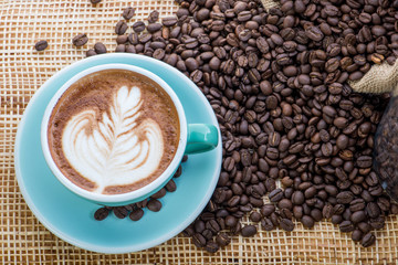 Cup of coffee on coffee beans background on a wooden table