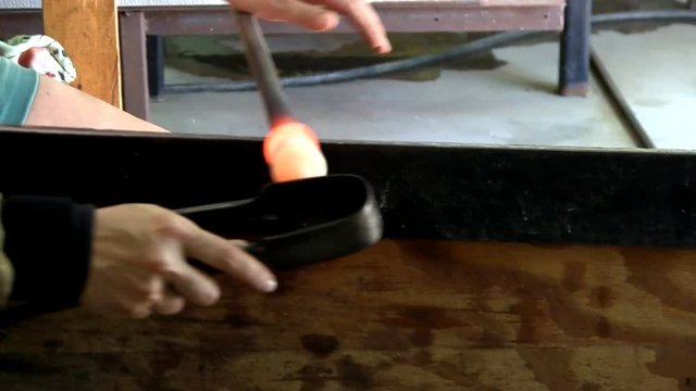Small glass gather being rounded on end of blowpipe by gaffer