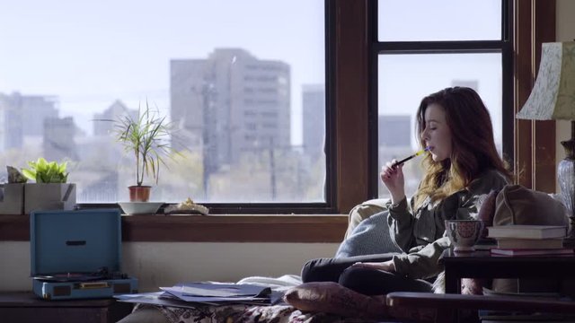 Young Woman Listens To A Record In Her Trendy Studio Downtown, She Uses A Vaporizer