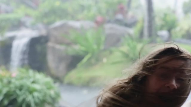 Happy Teen Girl Spins In Circle In Rain Storm, Her Hair Blows In Wind, Tropical Waterfall In Background, Maui, Hawaii