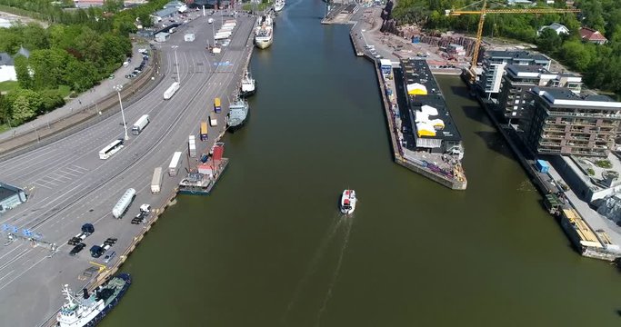 Turku, Cinema 4k aerial tilt up view flying over a cargo ship on aurajoki river and revealing abo cityscape, on a sunny summer day, in Turku, Finland