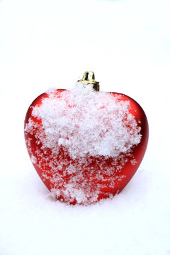 Red heart ornament in snow