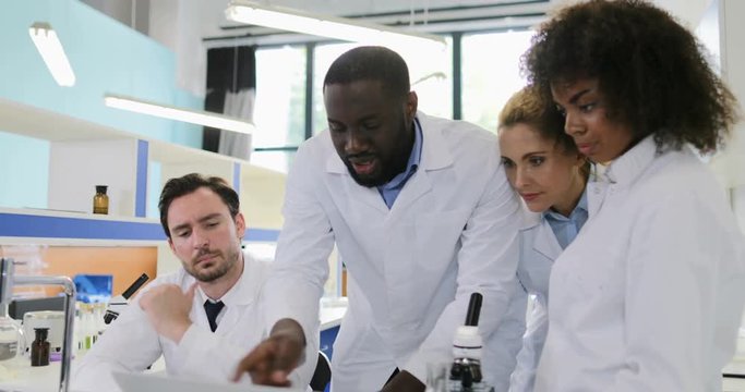 Diverse Group Of Scientists In Laboratory Looking At Laptop Computer Talking Discuss Analysis Examples And Experiment Results Slow Motion 60