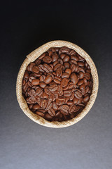 Coffee beans in the hemp sack on black wooden background.