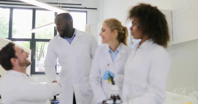 Group Of Scientific Workers Looking At Laptop Computer Male Researchers Handshake After Working Together On Experiments In Laboratory Slow Motion 60
