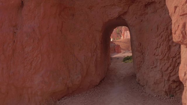 FPV: Hiking along empty path leading through stunning red rock Bryce Canyon National Park in Utah USA. Lonely hiking trail going past the sandstone hoodoos and eroded rocky pillars on sunny day