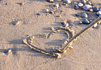 Heart drawn in sand with stick on clean beach