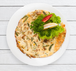 Omelette with asparagus, corn and vegetables. Healthy food, breakfast dish concept. White wooden planks background.