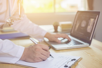Doctor working in hospital writing a prescription, Healthcare and medical concept,test results in background,Stethoscope with clipboard and Laptop on desk,vintage color,selective focus