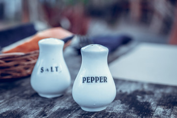 Glass salt and pepper shakers on a wooden table in restaurant, Bali island.