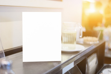 Mock up Menu frame on Table in Bar restaurant or coffee shop ,Stand for booklets with white sheets of paper acrylic tent card on cafeteria ,barista preparing cup of coffee for customer in background.