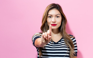 Young woman pointing something on a pink background