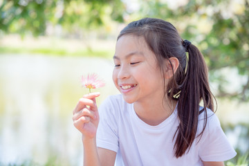 Obraz premium Young asian girl holding flower and smiles