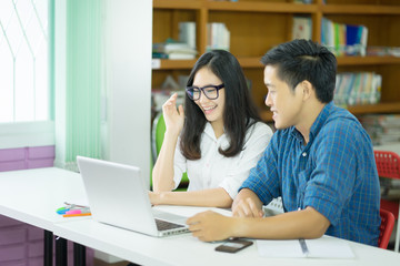 students taking notes preparing exam and learning lessons from  book at library. people, education, technology and school concept,happy students with laptop computer and books in campus school library