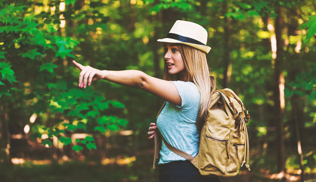 Young woman in the forest with a backpack and hat