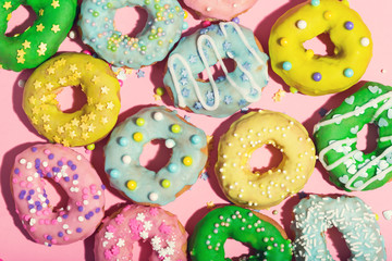 Colorful glazed donuts on a pink background