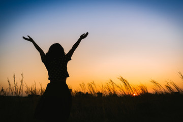 silhouette of woman open arms under the sunset