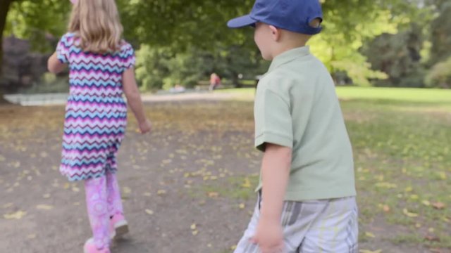 Silly Little Kids (Brother And Sister) Walk Funny On A Park Path In Autumn (Slow Motion)