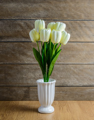 white tulip flowers bouquet in vase on wooden floor