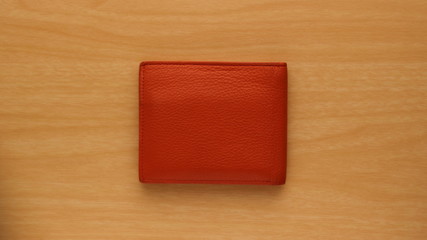 orange leather wallet on wooden board background