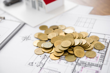 Money on blueprint paper with blurred house model in background