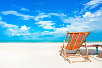 Colorful beach chair on white sand beach in bright blue sky background