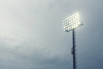 Spotlight under nimbus sky at the stadium at night time.