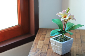 artificial plumeria flowers in pot on wooden table