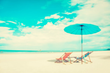 Fototapeta na wymiar Blurred white sand beach with beach chairs and parasol