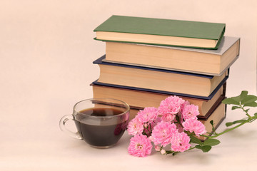A stack of books with flowers and coffee.