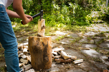 Young man with axe chopping wood on a chopping block