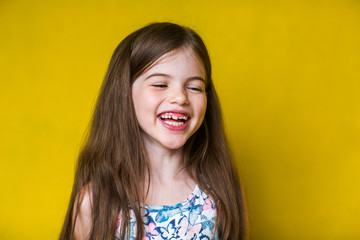 Portrait of cheerful smiling little cute little girl on yellow background isolated