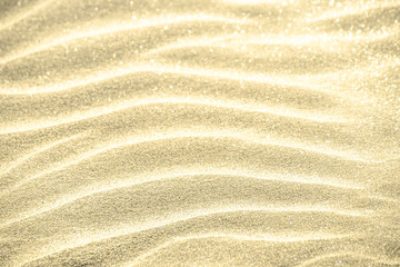 Golden glitter on sand background