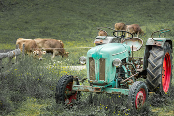 Old tractor on meadow. Beautiful mountain view in the Alps