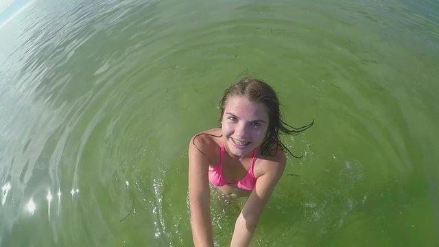 Excited Teenage Girl Spins In Circles In Ocean, With Gopro Stick