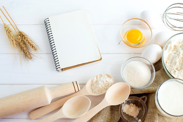 Ingredients for cooking buns: flour, egg, yolk, sugar, vanilla, spikelets on a white wooden background