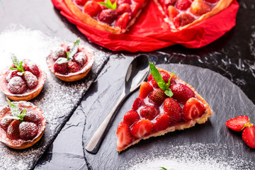 Strawberry pie and tart on black slate plate. Mix desserts. Top view.