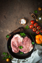 Raw pork meat in the pan. Top view copy space stone background.