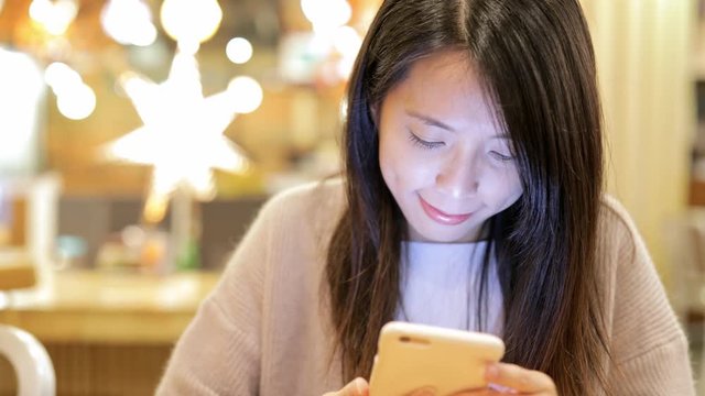 Woman working on mobile phone inside restaurant